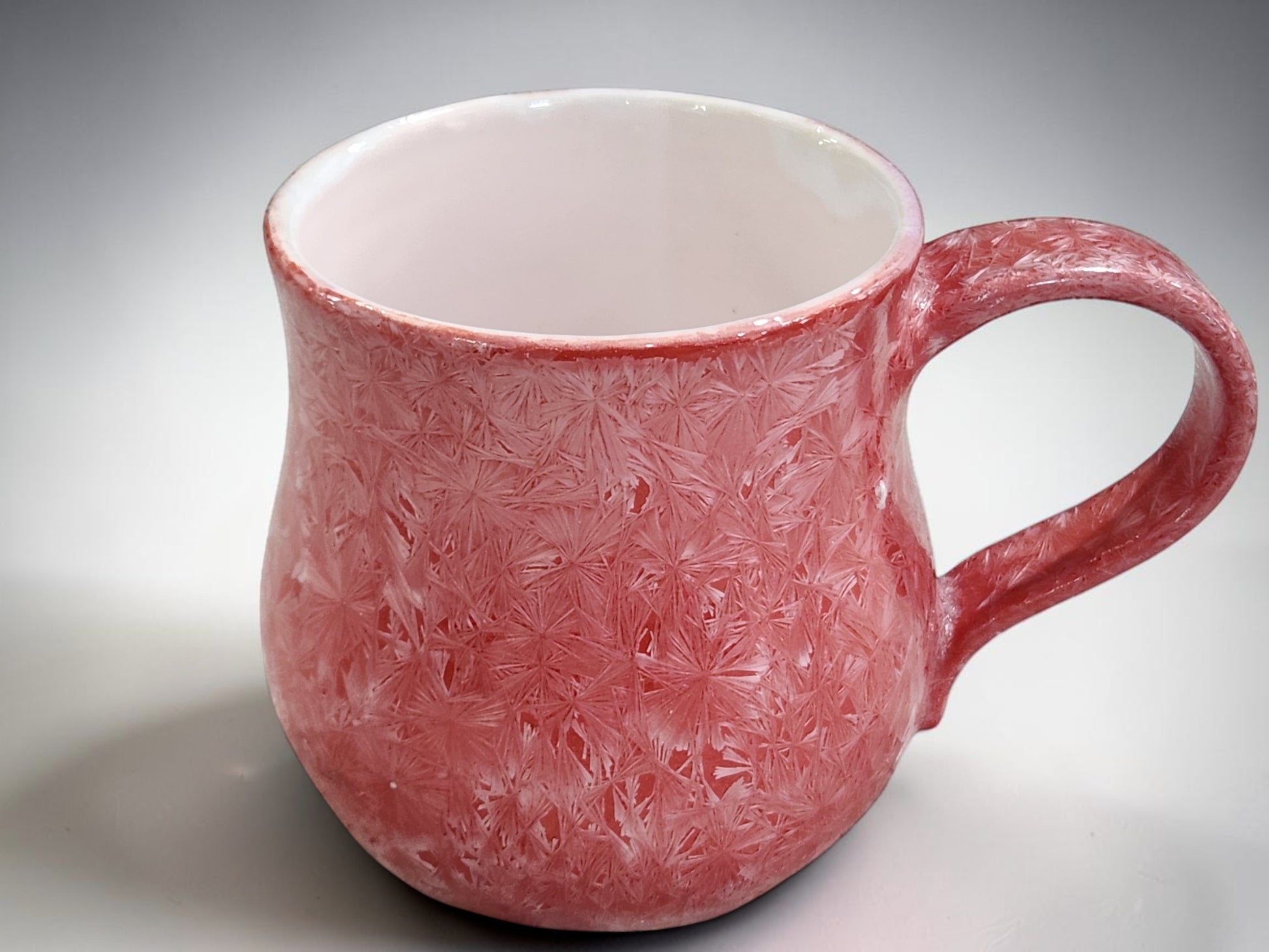 Detailed crystalline glaze pattern on handmade red pottery mug