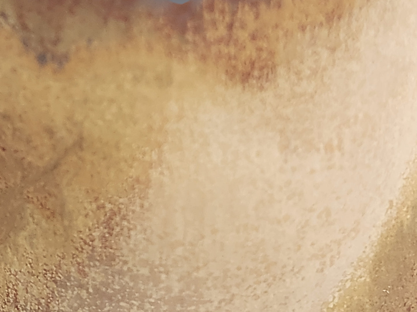 Close-up of handmade ceramic mug showing flowing oatmeal and earthy brown glaze detail