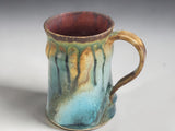 Side view of a wheel-thrown handmade ceramic mug with comfortable hand-pulled handle.