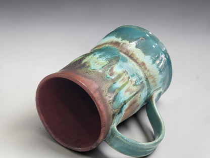 Detailed close-up of the flowing turquoise and iron brown glaze on a handmade mug.