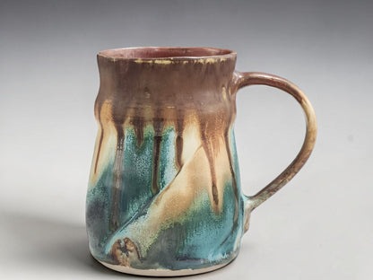 Close-up of flowing turquoise, cream and chestnut glaze on handmade Australian pottery mug