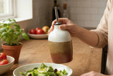 Handmade ceramic oil bottle with speckled cream and earthy glaze