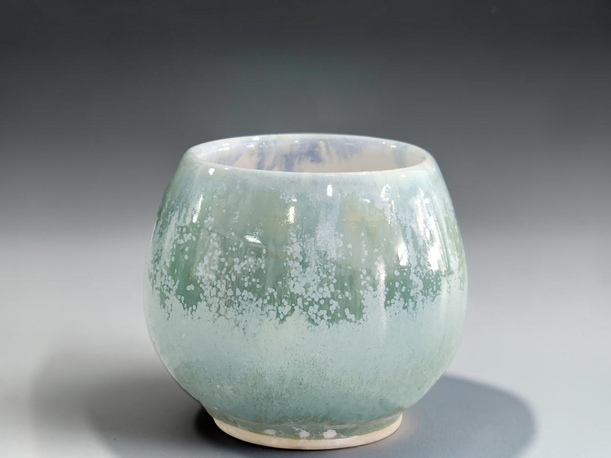 Small soft green ceramic drinking cup with white mottled glaze detail