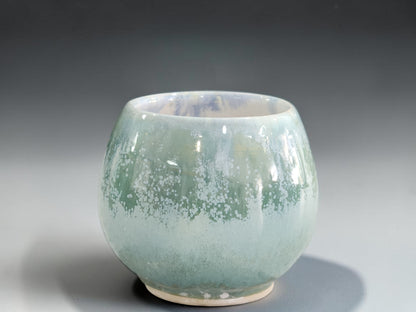 Small soft green ceramic drinking cup with white mottled glaze detail