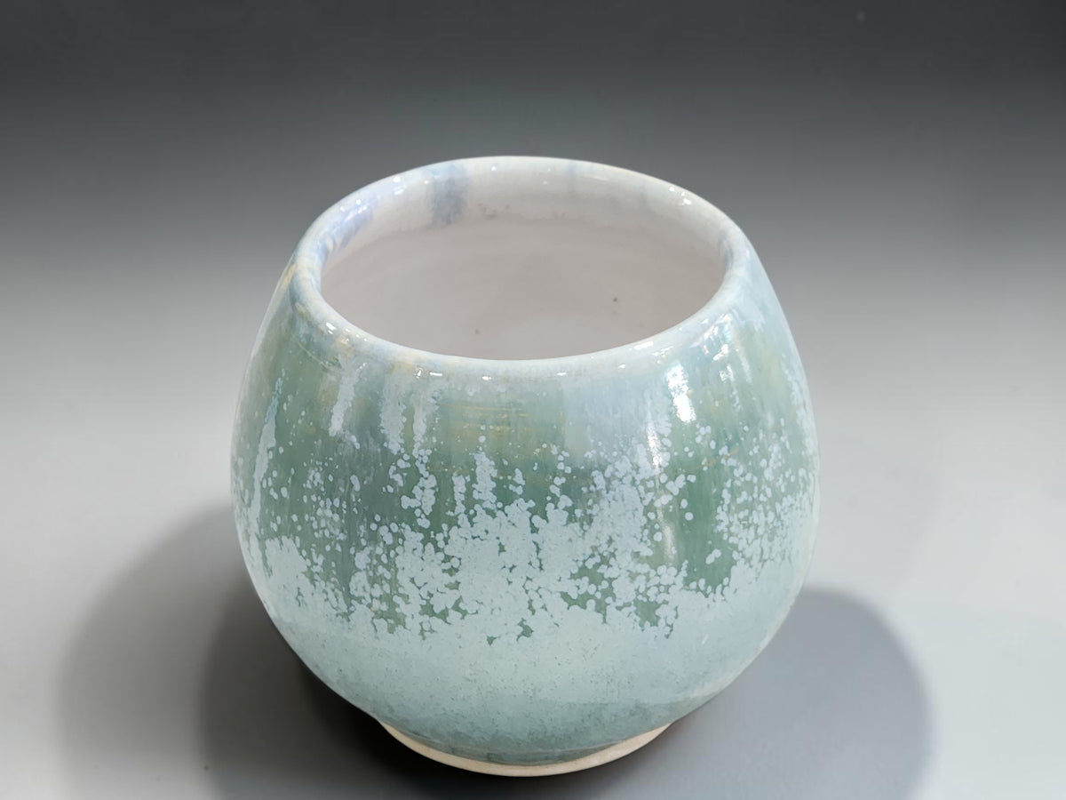 Soft green handmade stoneware cup with unglazed clay foot ring