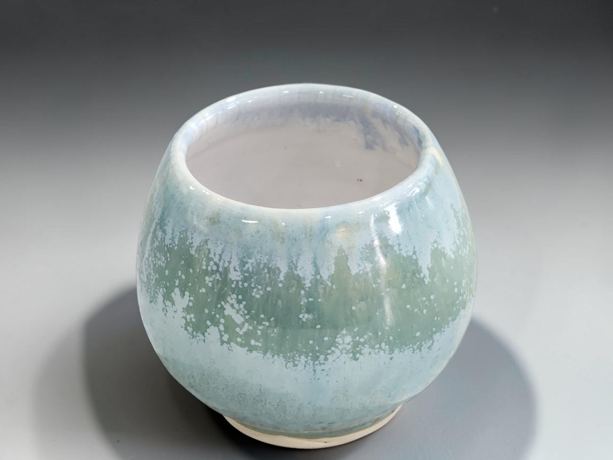 Front view of rounded green ceramic tea and whisky cup