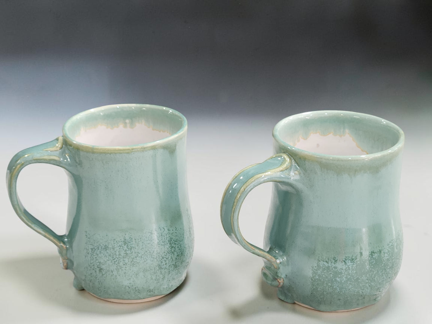 Handmade spearmint green pottery mugs with drippy glaze detail