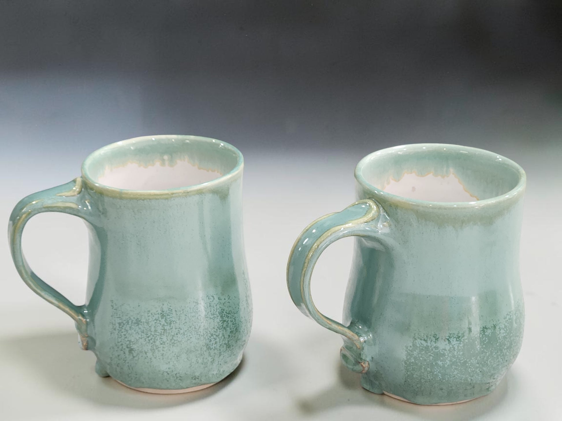 Handmade spearmint green pottery mugs with drippy glaze detail