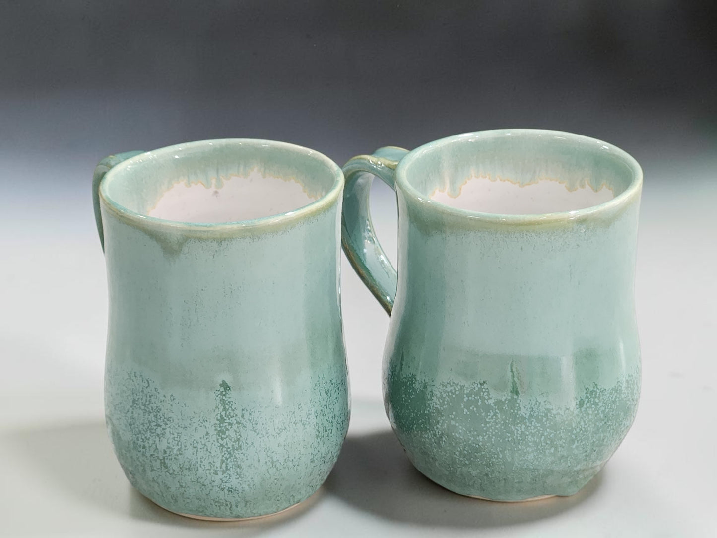 Large ceramic coffee mugs with layered green glaze and natural drips