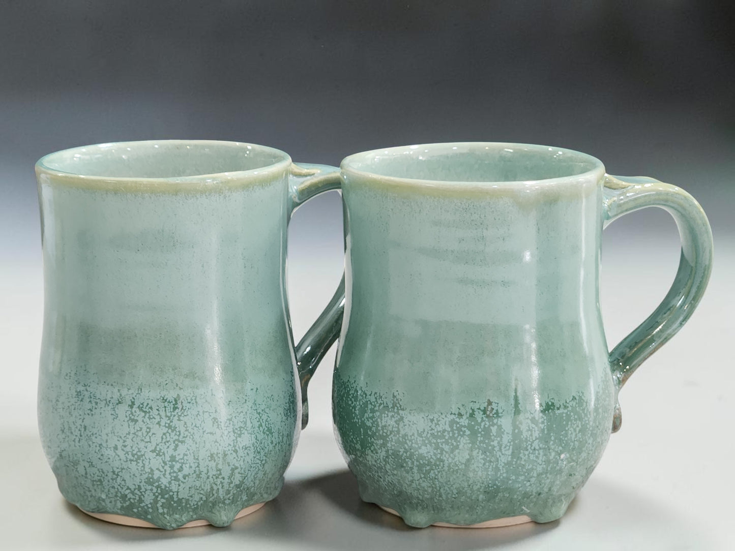 Spearmint green mugs with darker flowing glaze at the bottom