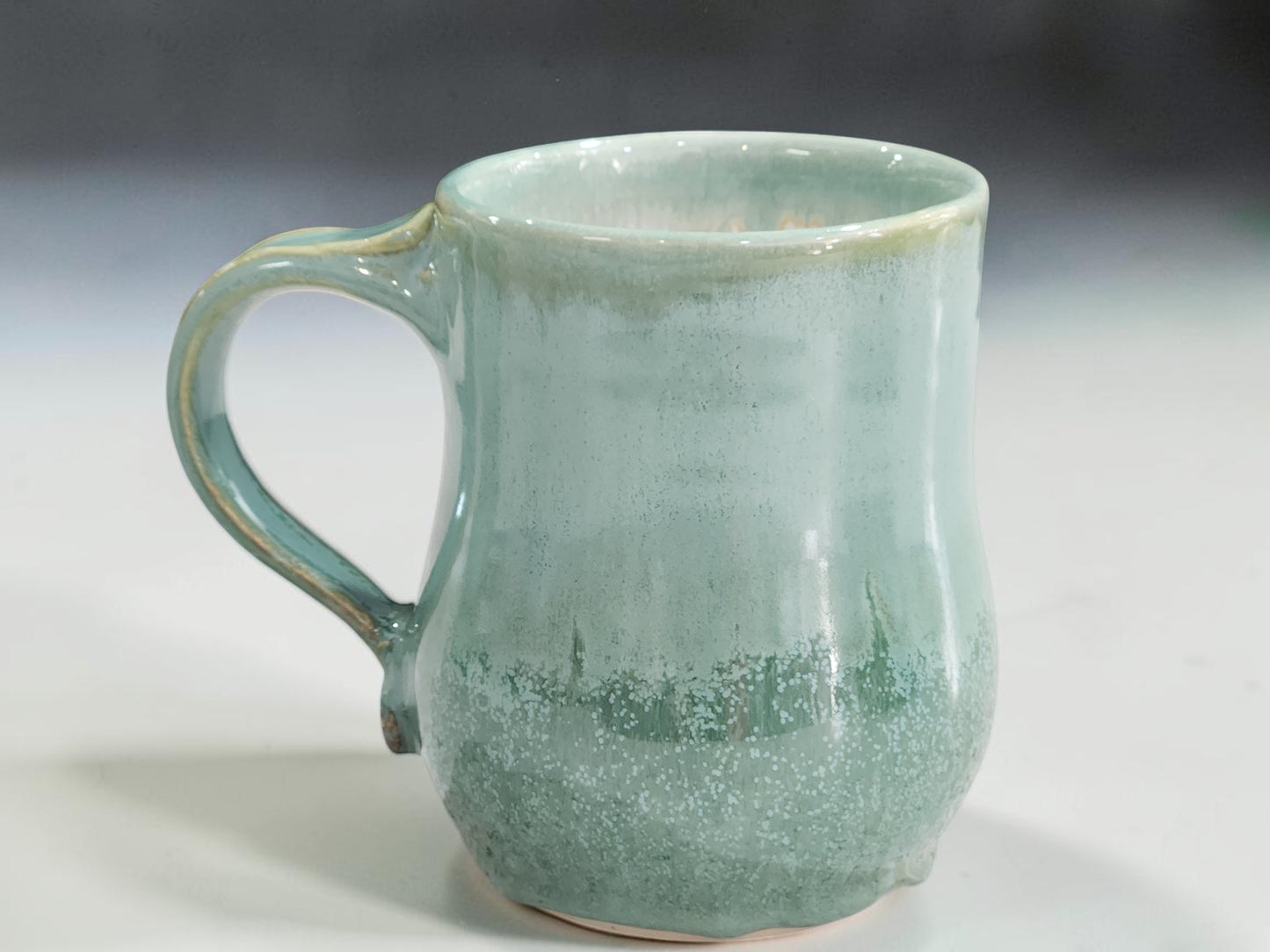 Wheel-thrown pottery mug with glossy glaze and dripped lower edge
