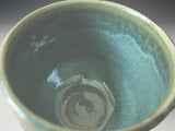 Close up of the glossy green mottled interior glaze of a tea cup