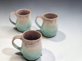 Top view of three handmade stoneware mugs with smooth glazed interiors, ceramic pottery mugs