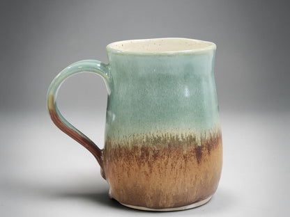 Tall ceramic mug with soft green and earthy brown glaze