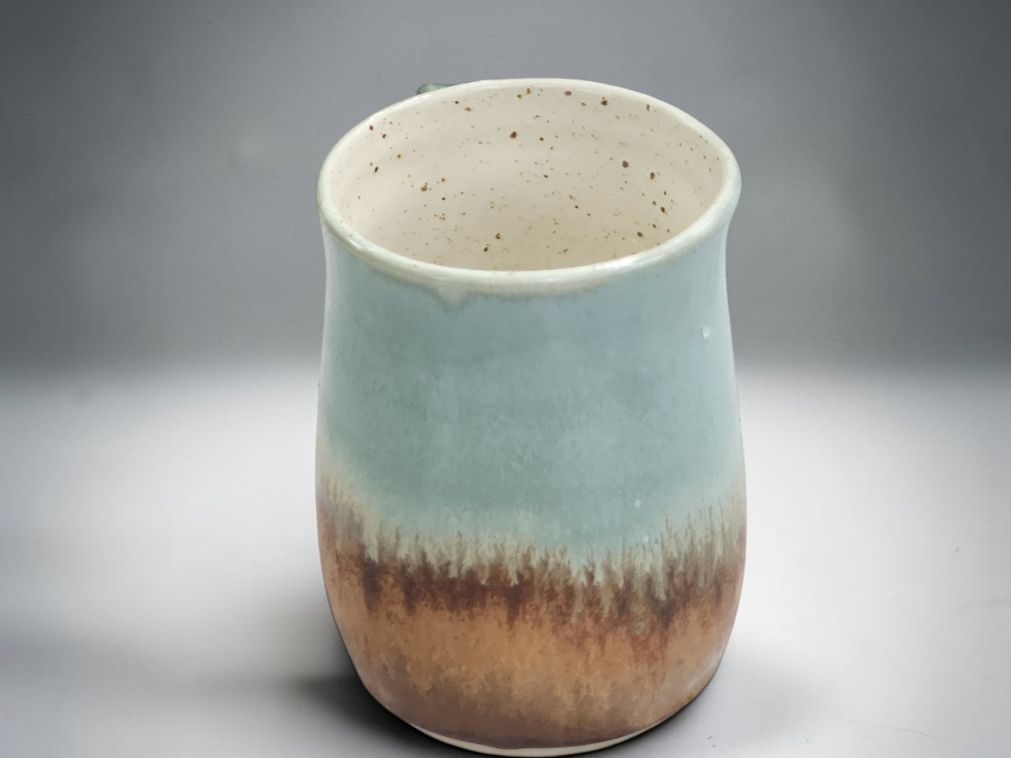 Tall pottery mug with rustic earthy tones and glossy finish