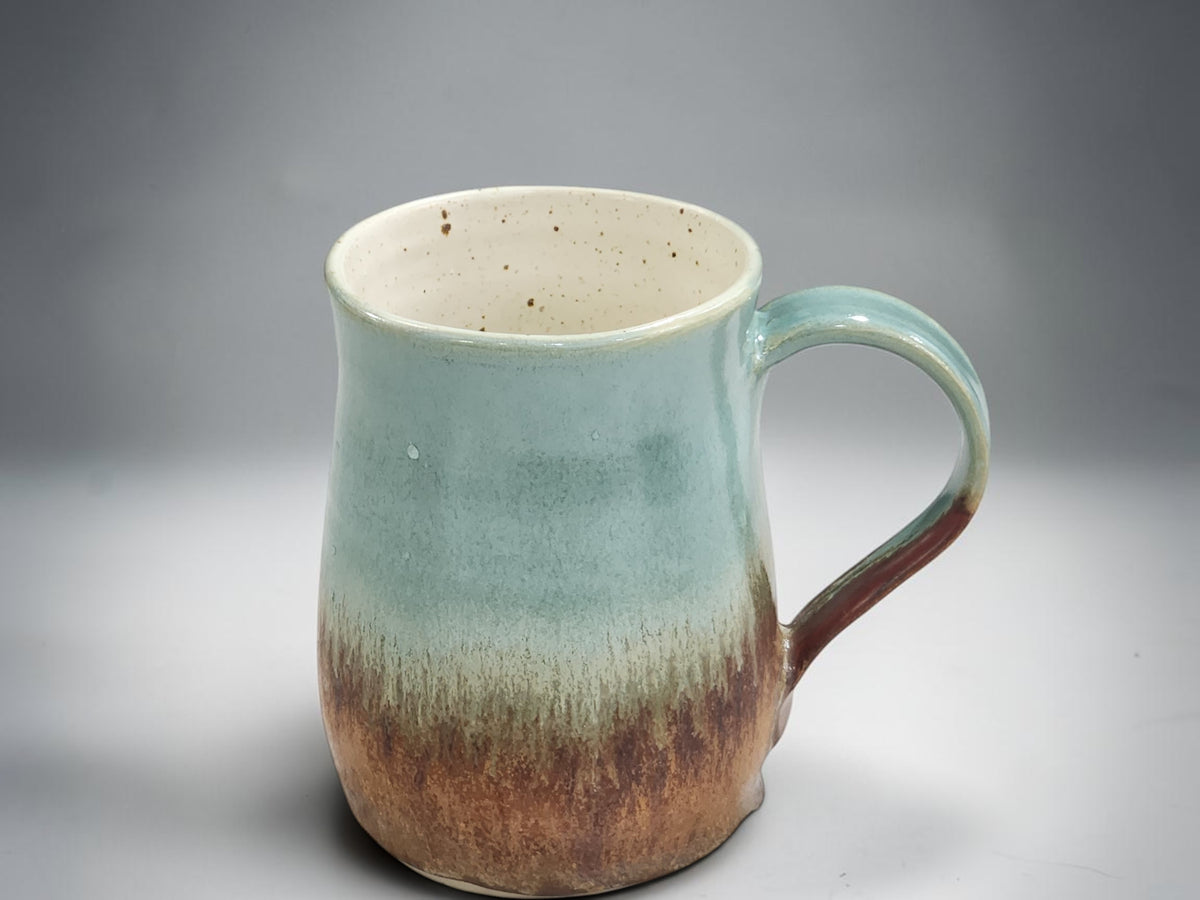 Handmade tea mug with curved handle and flowing glaze