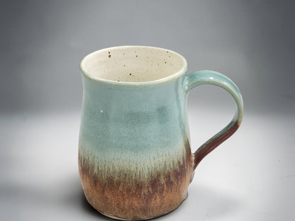 Handmade tea mug with curved handle and flowing glaze
