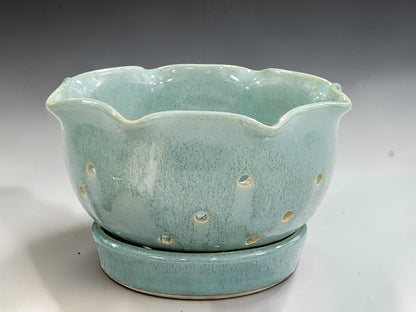 Handmade ceramic berry bowl with drainage holes and matching saucer in soft green glaze