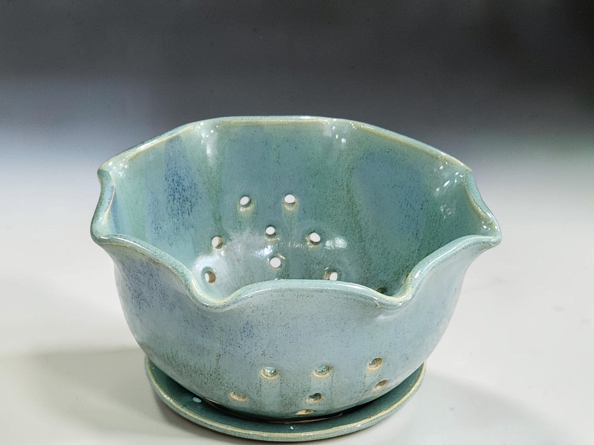 Green pottery berry bowl with scalloped rim and drainage holes