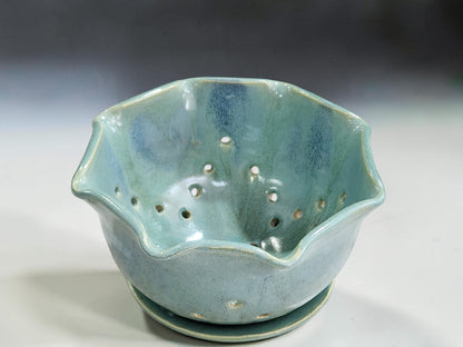 Spearmint green ceramic colander bowl on matching saucer