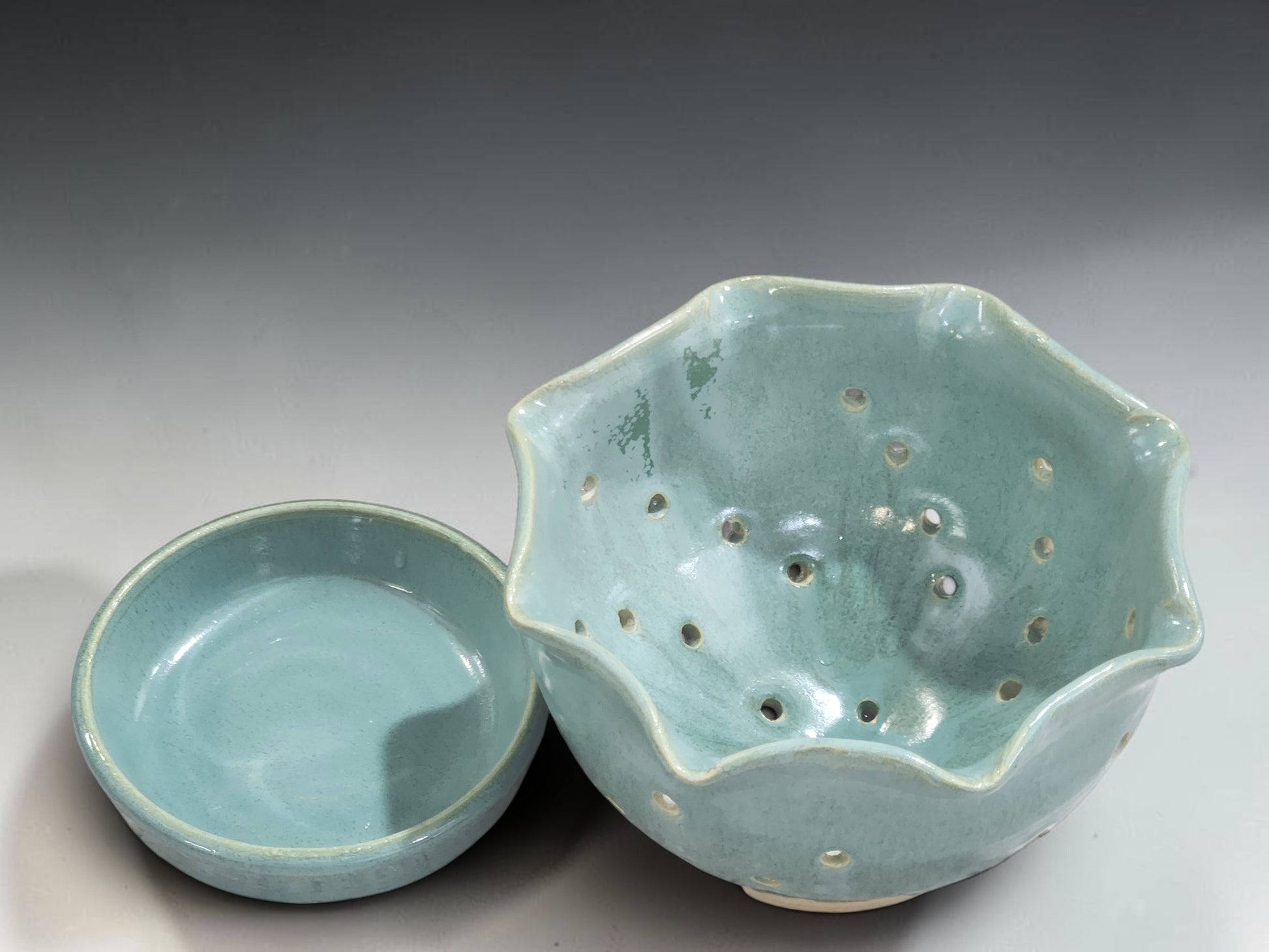 Decorative handmade fruit rinsing bowl in pale green glaze with pierced drainage holes
