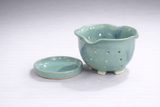 Small green pottery strainer bowl with blue mottled detail