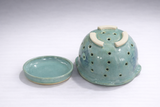 Green stoneware berry bowl with drainage holes and matching base