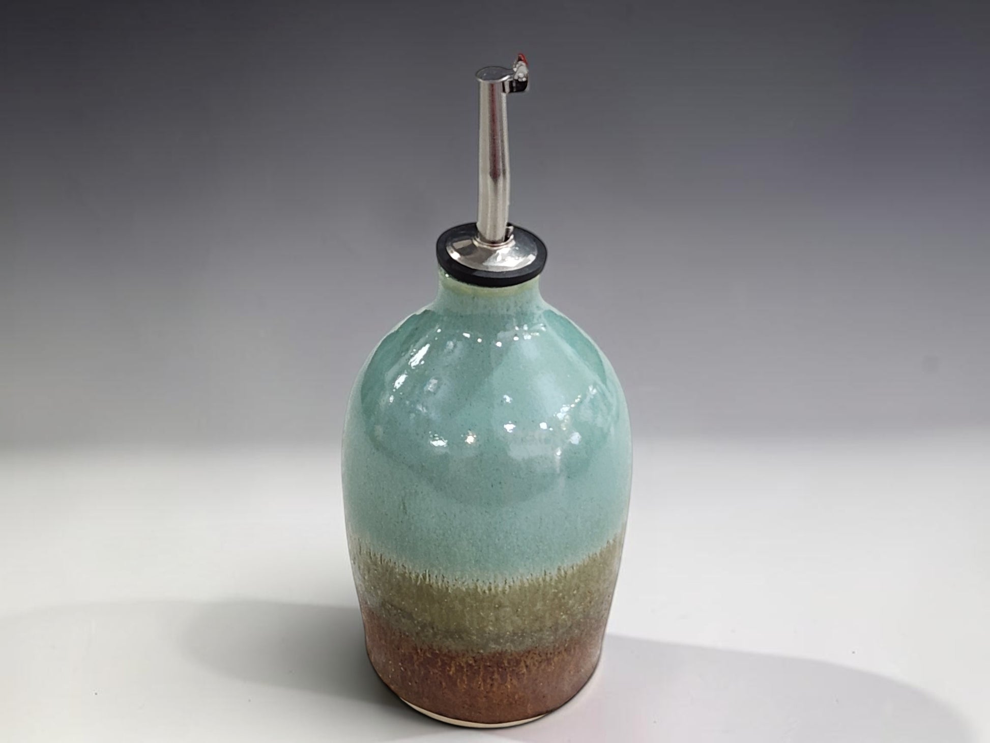 Ceramic olive oil bottle in spearmint green and earthy terracotta glaze for everyday kitchen use