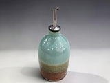Ceramic olive oil bottle in spearmint green and earthy terracotta glaze for everyday kitchen use