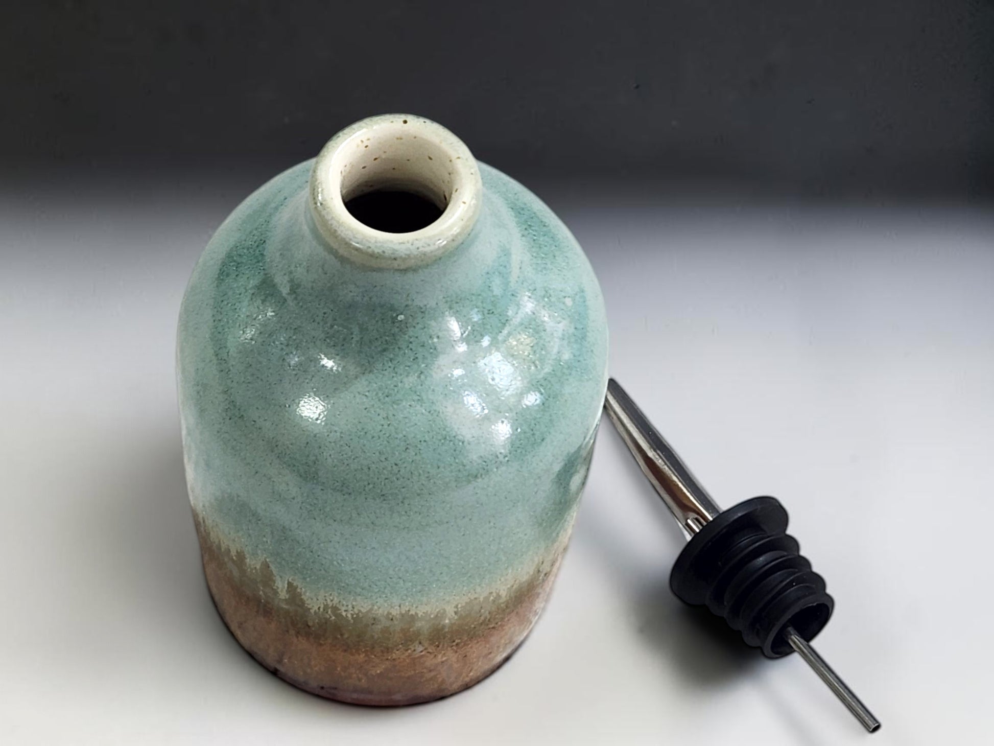 Stainless-steel pouring spout fitted to handmade ceramic oil bottle