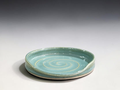 Spearmint green handmade pottery spoon rest with spiral design for resting cooking spoons and kitchen utensils.