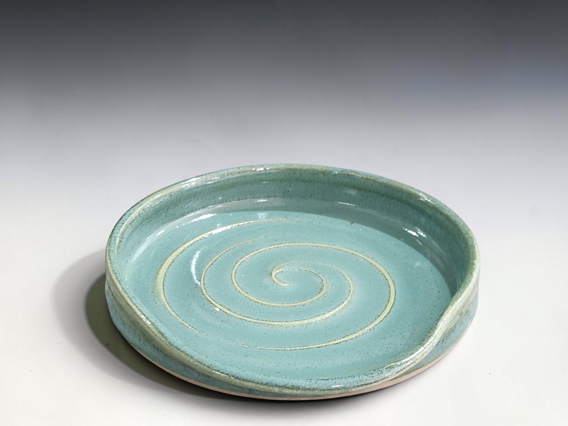 Wheel-thrown ceramic spoon rest in spearmint green with carved spiral detail, handcrafted in Melbourne.