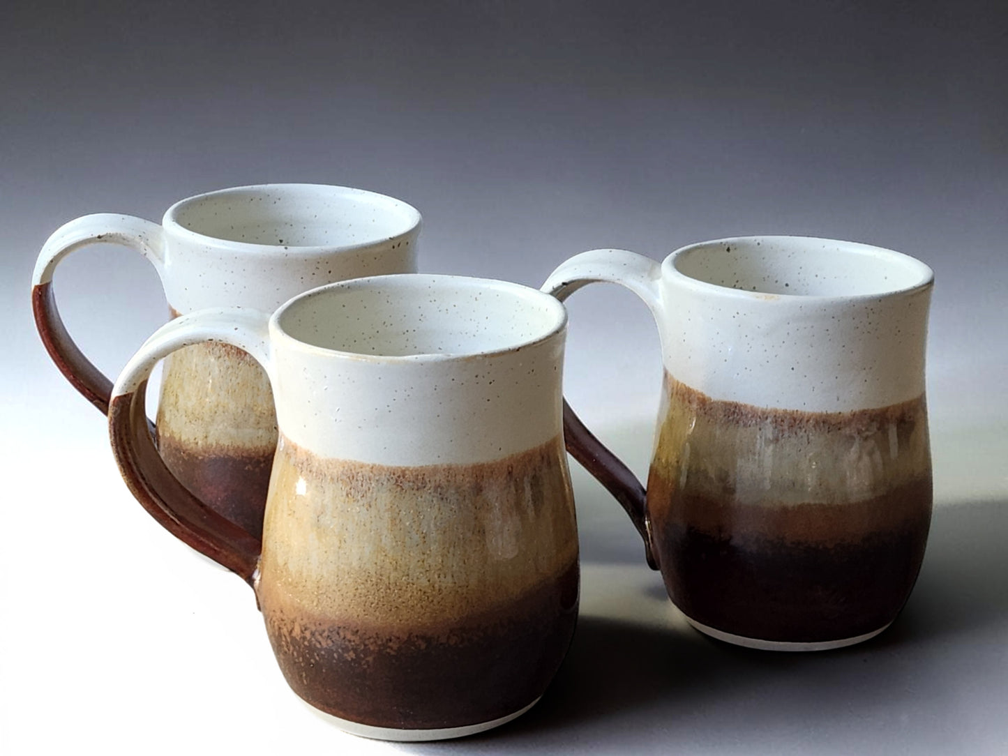 Large handmade red-brown and cream pottery mugs with layered glaze