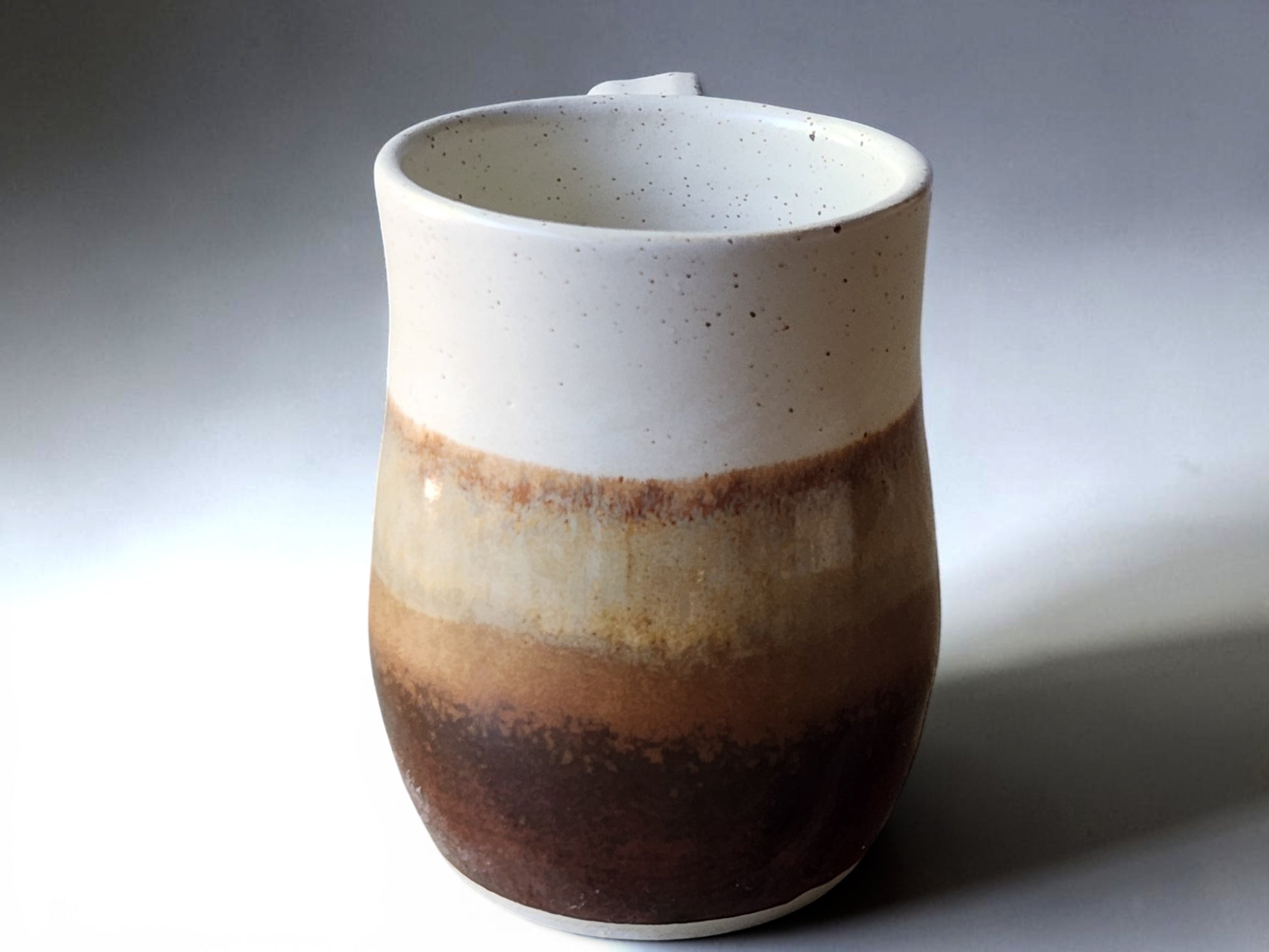 Wheel-thrown pottery mug with handmade curved handle