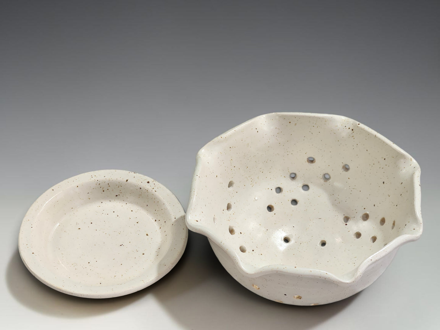 Handmade pottery fruit bowl with drainage holes and matching drip tray for everyday kitchen use