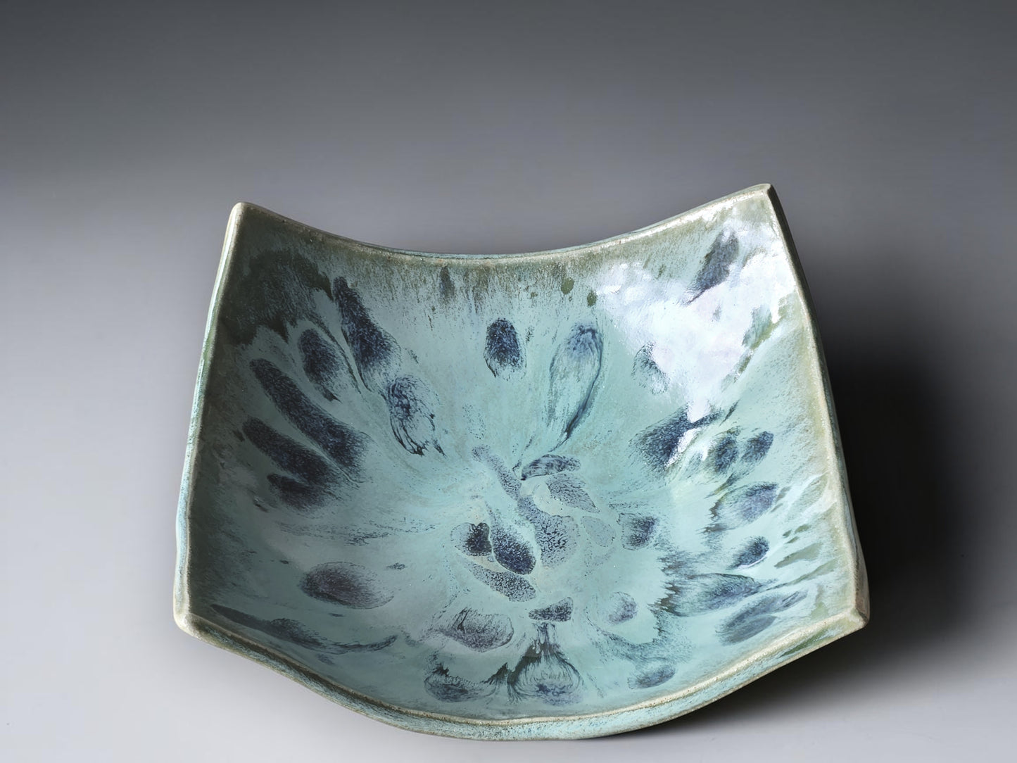 Decorative ceramic fruit bowl with flowing corners and textured blue interior finish