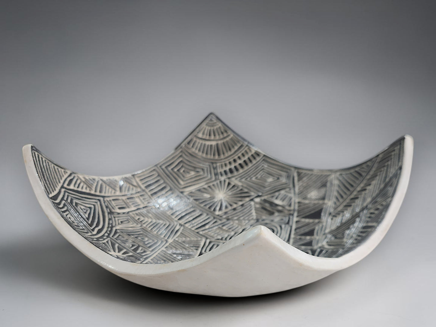 Artisan pottery bowl featuring hand-carved black and white abstract linework