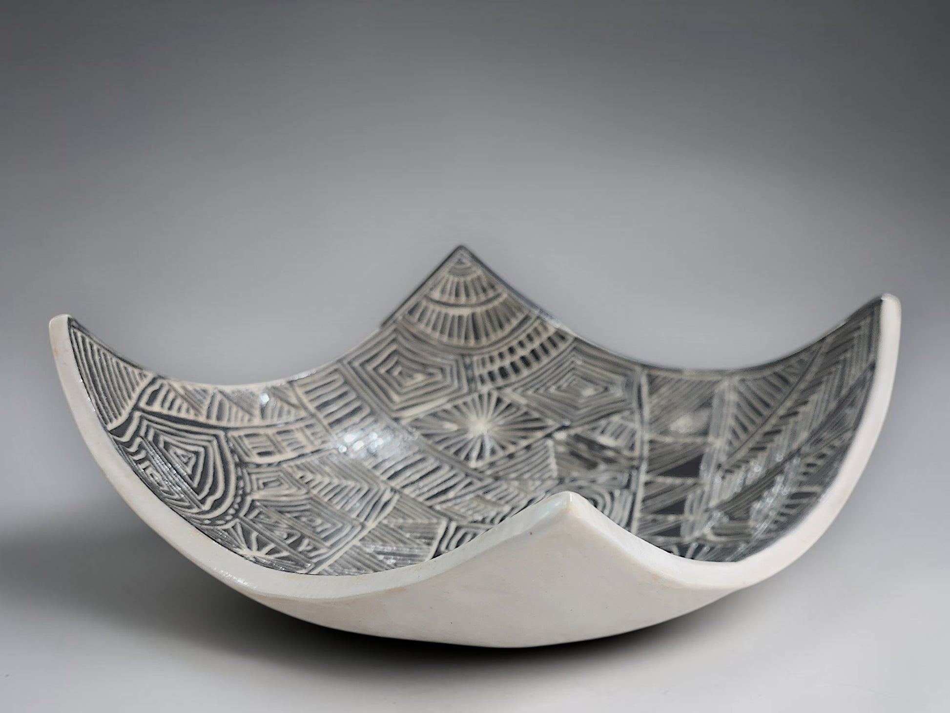 Artisan pottery bowl featuring hand-carved black and white abstract linework