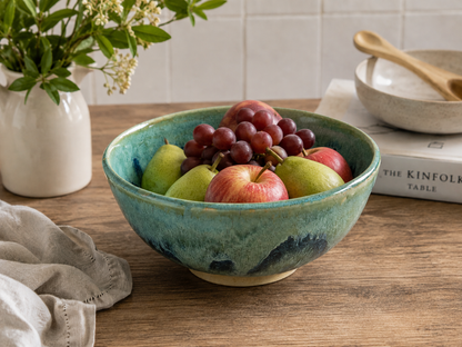 Handmade Australian ceramic fruit bowl in mottled green glaze displayed with fresh seasonal fruit in a contemporary kitchen setting by Buxton Pottery.
