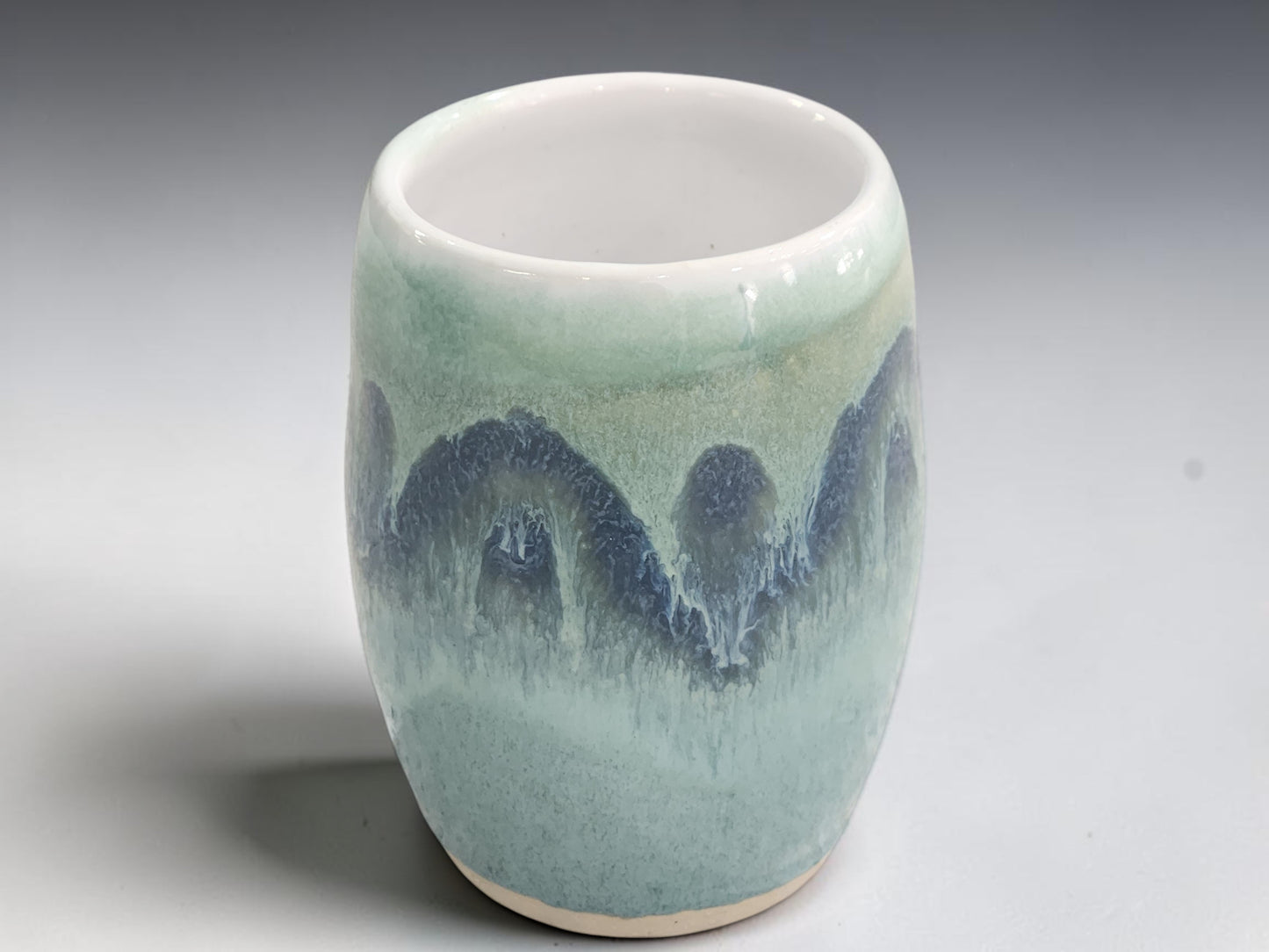 Wheel-thrown pottery vase with landscape-inspired green and blue glaze.