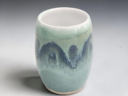 Wheel-thrown pottery vase with landscape-inspired green and blue glaze.