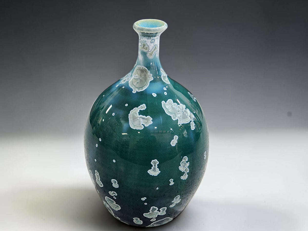 Angled view of the decorative green vase showing its curved shoulders and pale crystal patterns.