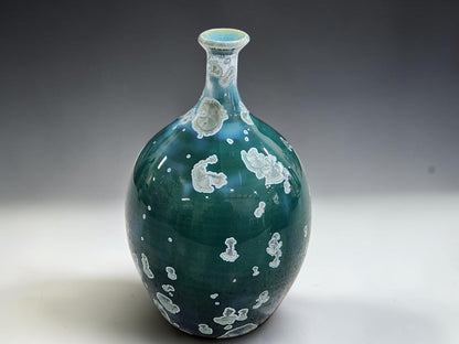 Angled view of the decorative green vase showing its curved shoulders and pale crystal patterns.