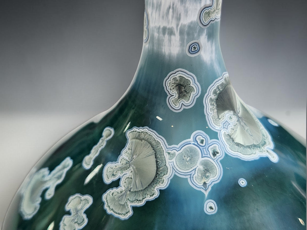 Detail of the small flared rim and slender neck of the teal-green crystalline vase