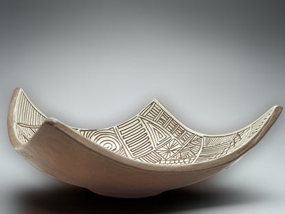 Decorative ceramic centerpiece bowl featuring hand-etched patterns in white slip finish