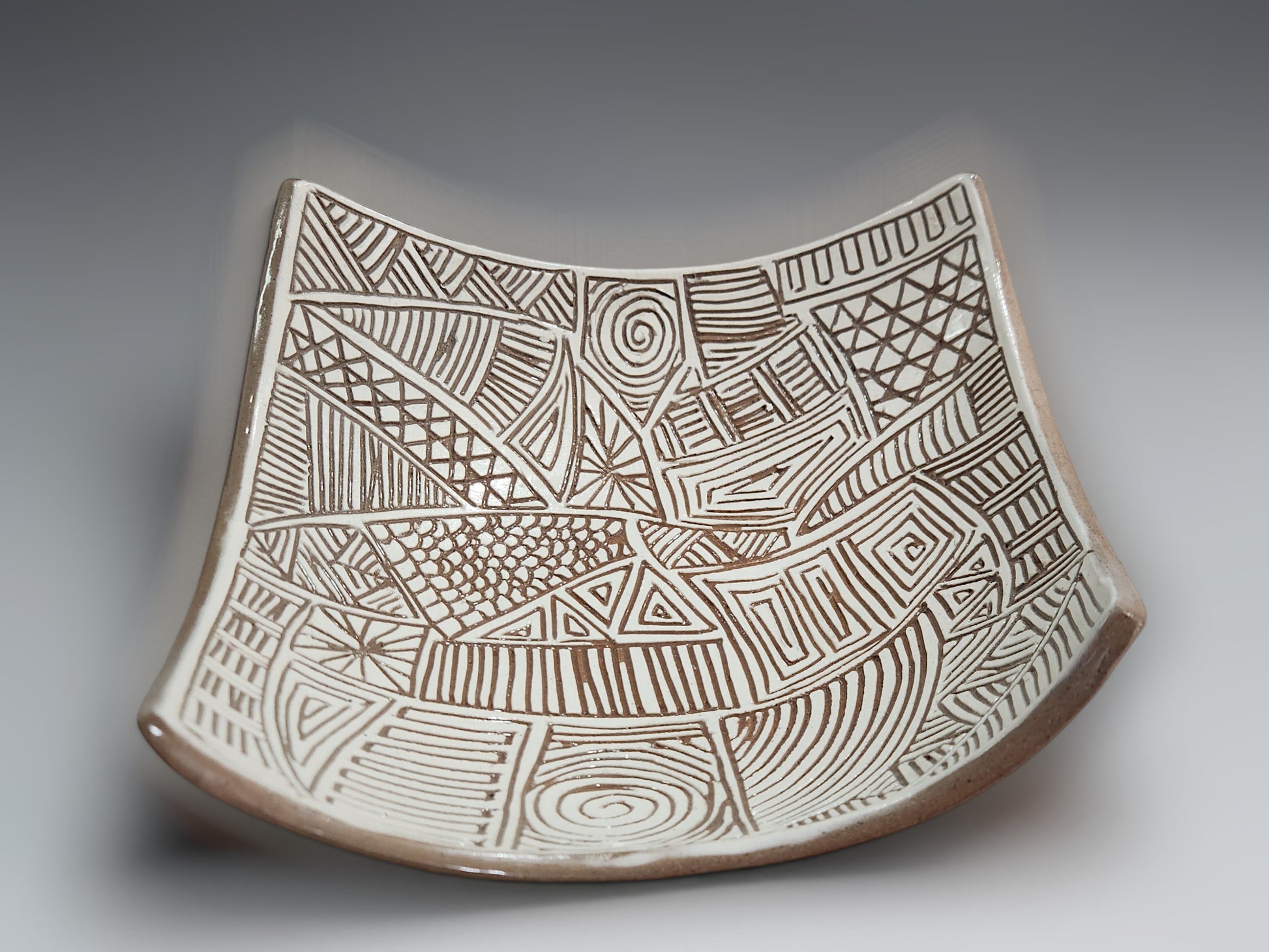 Artisan pottery bowl with carved white slip interior and sculptural curved silhouette