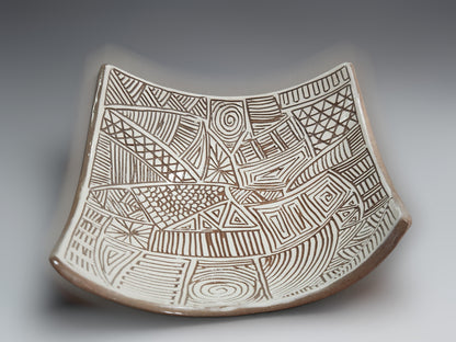 Artisan pottery bowl with carved white slip interior and sculptural curved silhouette