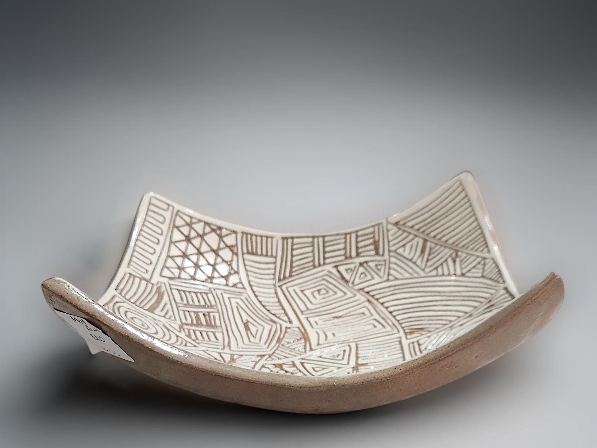 Unique carved ceramic fruit bowl with tribal-inspired white slip decorative pattern