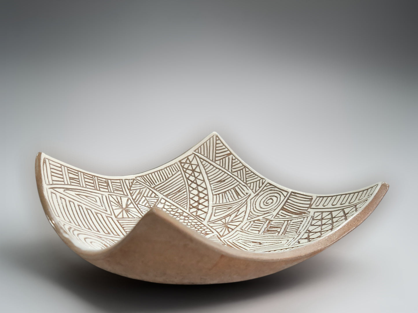 Modern artisan pottery bowl with abstract etched interior and flowing draped edges