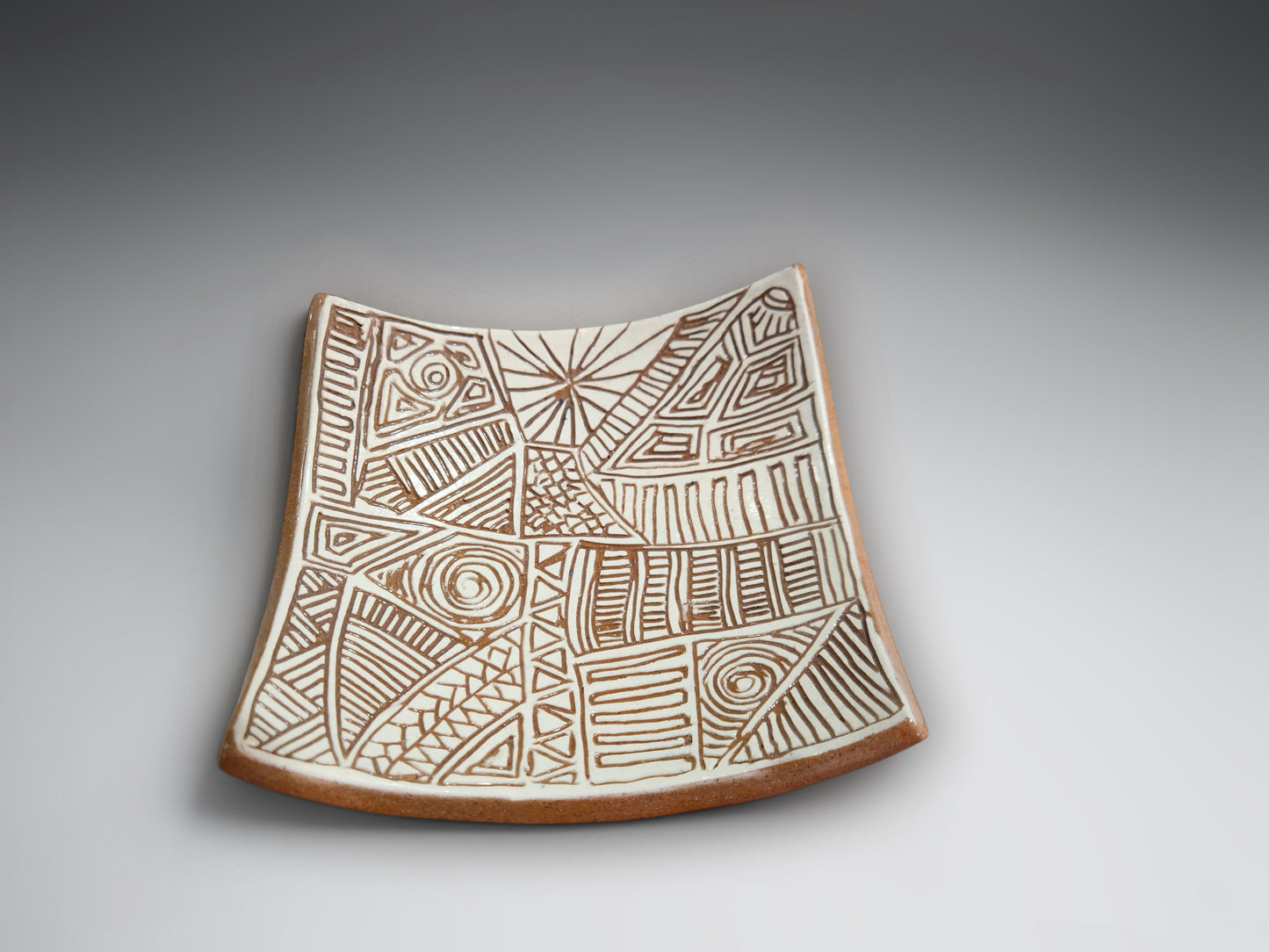 Small handcrafted terracotta bowl-plate with carved tribal-inspired geometric detailing